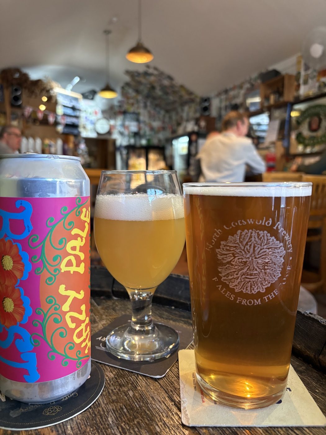 A craft beer can and pints on a table