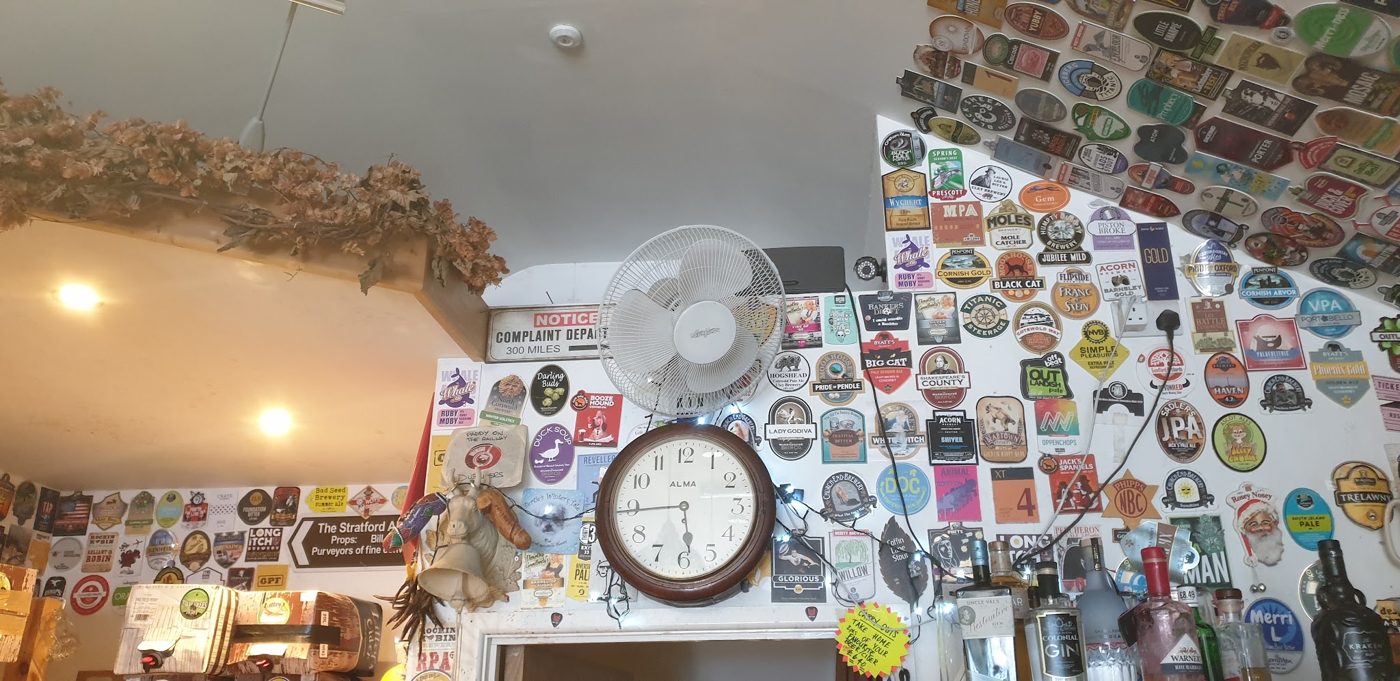 A wall covered in beer mats, with a clock