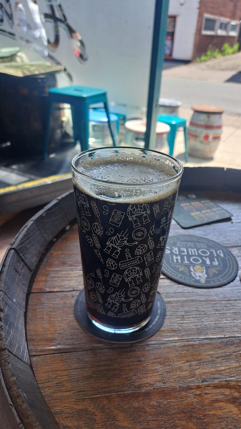 A dark pint on a barrel by the window